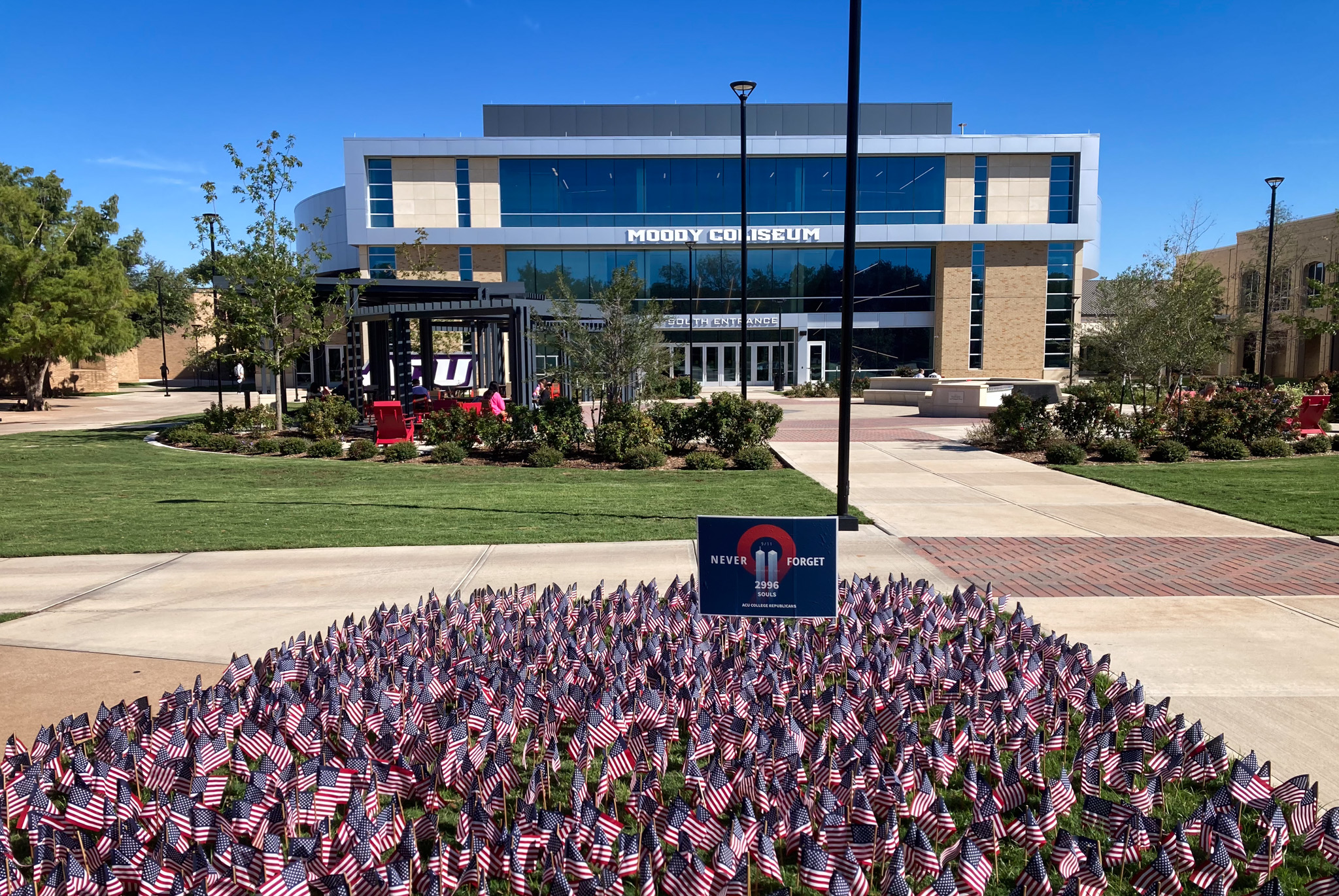 Hundreds of small U.S. flags are seen surrounding a 9/11 memorial in front of a campus building.