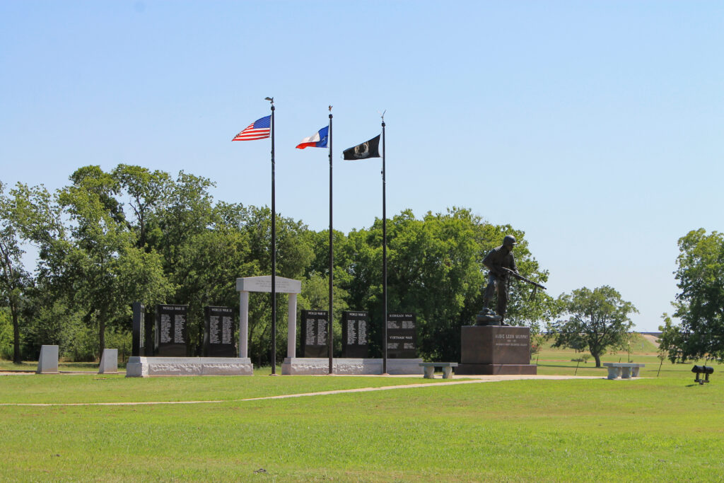 An outside photo of the museum shows a memorial and a statue of Audie Murphy along with three flags: an American flag, a Texas flag, and a POW/MIA flag.