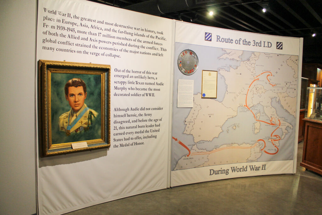 A war exhibit in the museum shows a portrait of Audie Murphy and a map showing his movement in WWII.