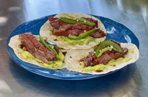 Three meat tacos on a blue plate